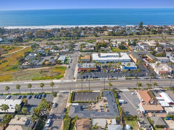 An aerial view of a coastal town with a marina, a large commercial building, and residential areas.