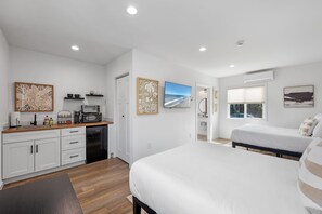 A modern bedroom with a large bed, a separate bathroom, and a kitchenette.