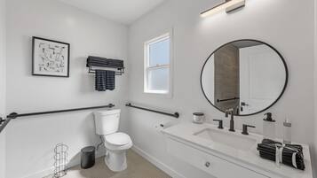 Un baño moderno con inodoro, lavamanos, espejo, toallero y ventana.