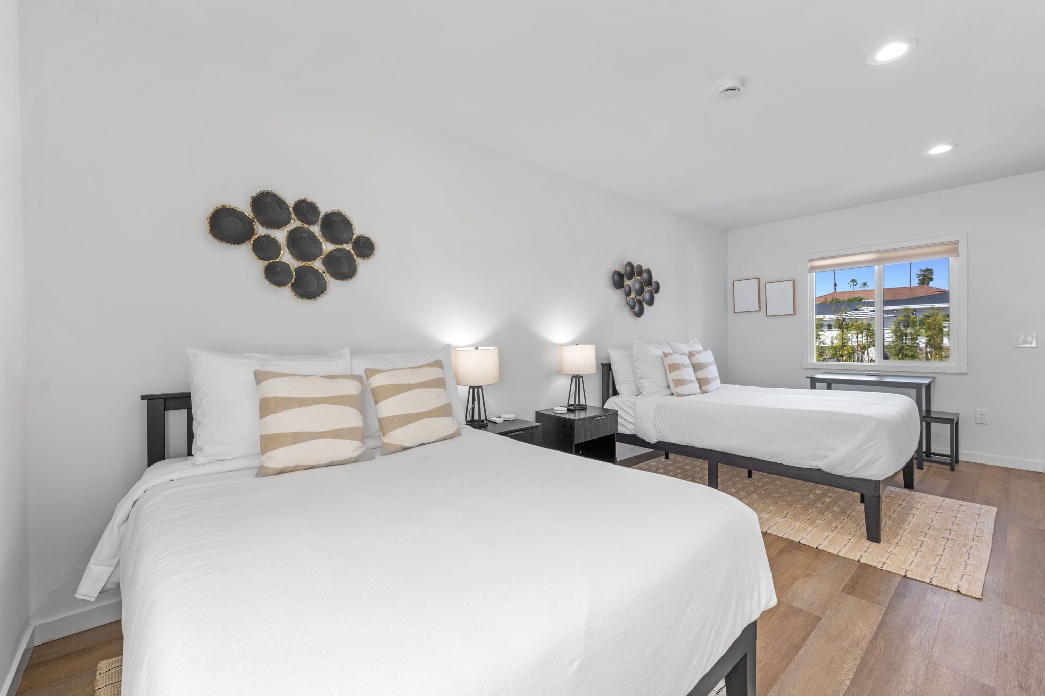 Habitación de hotel con dos camas, un ventanal grande y decoración mural.