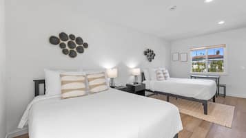 Habitación de hotel con dos camas, un ventanal grande y decoración mural.