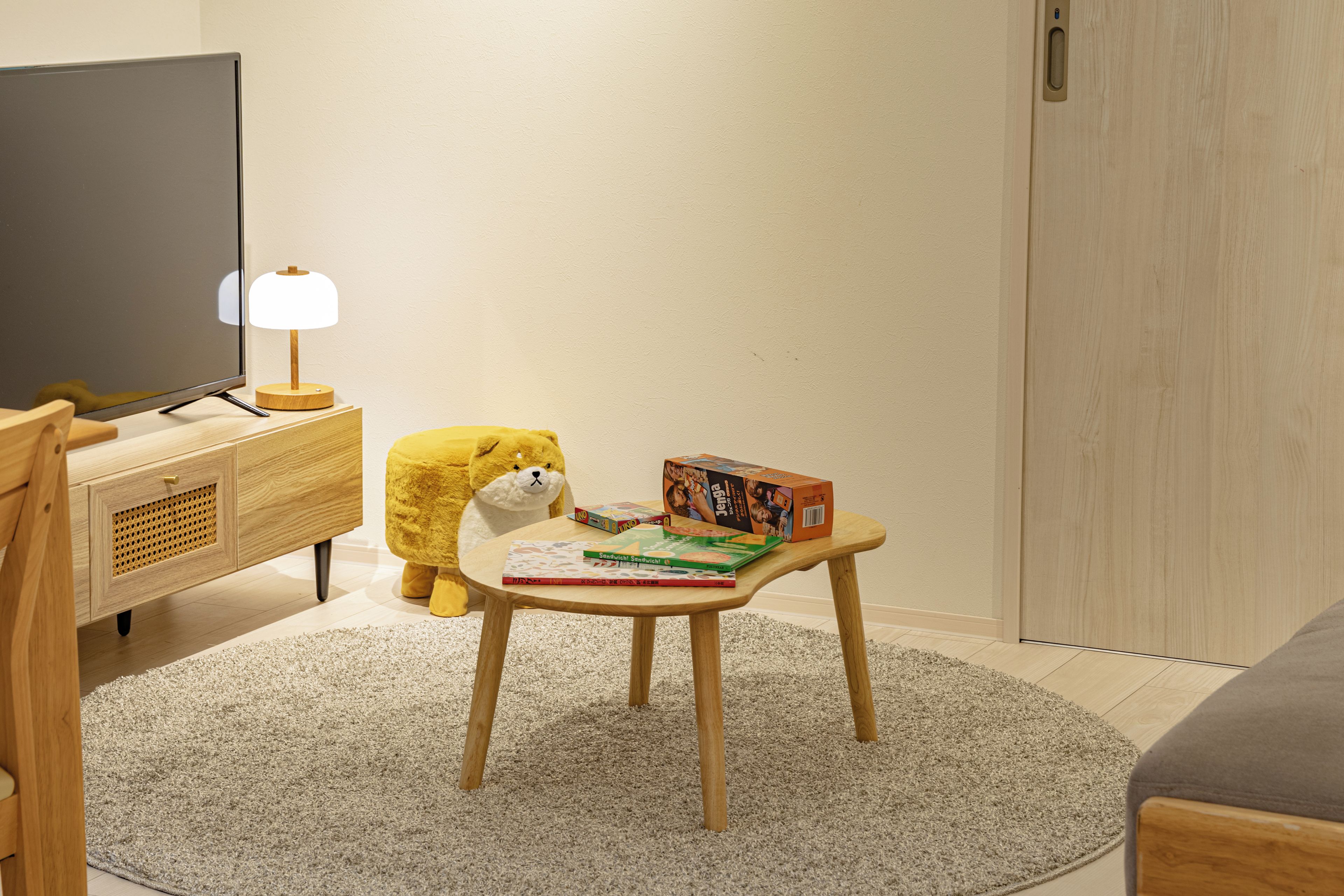 Une pièce avec une télévision, une petite table avec des livres et un jouet, et un canapé.