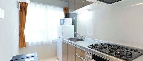 A compact kitchen with a gas stove, a sink, and a refrigerator.