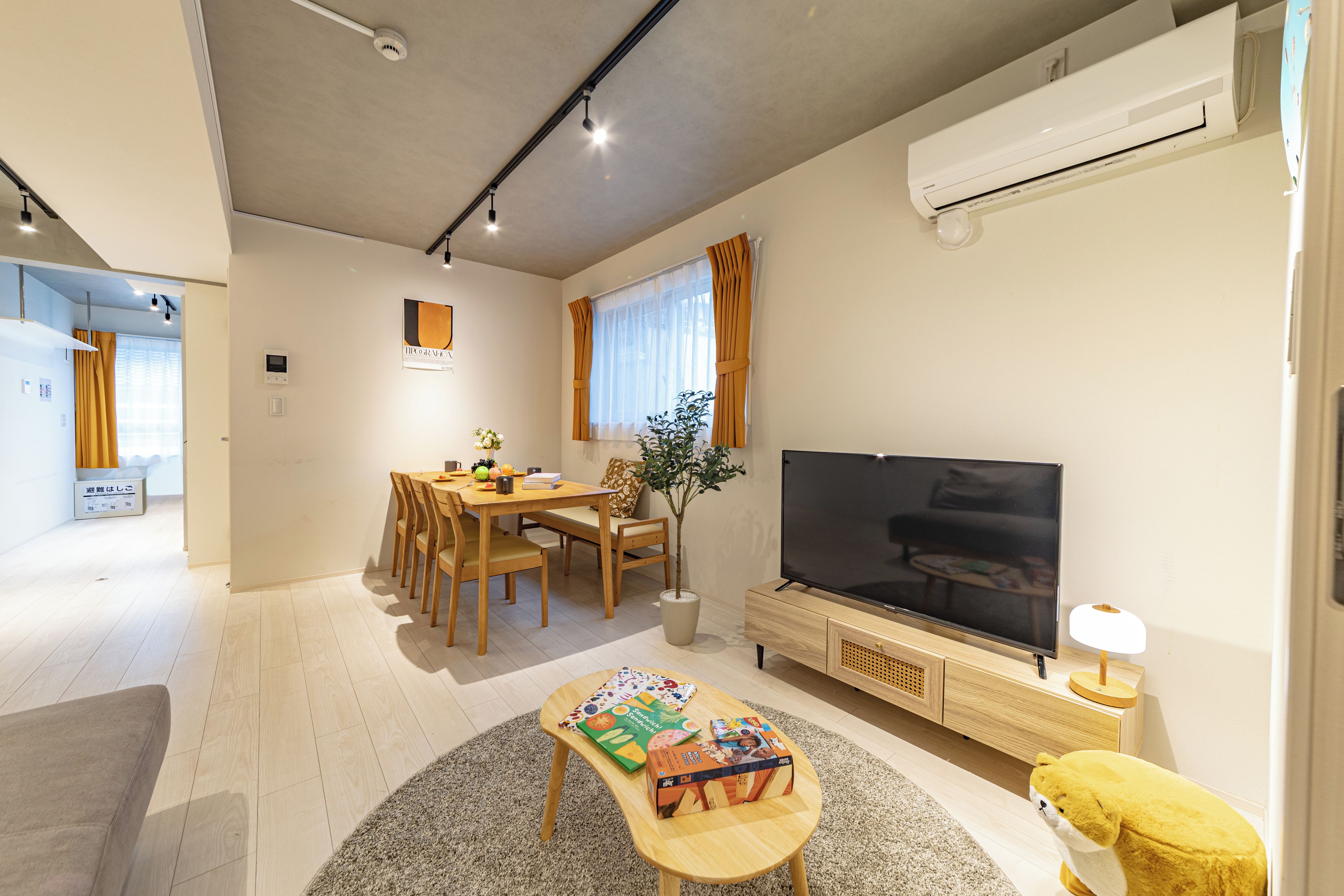 A modern living room with a dining area, a flat-screen TV, and a sofa.