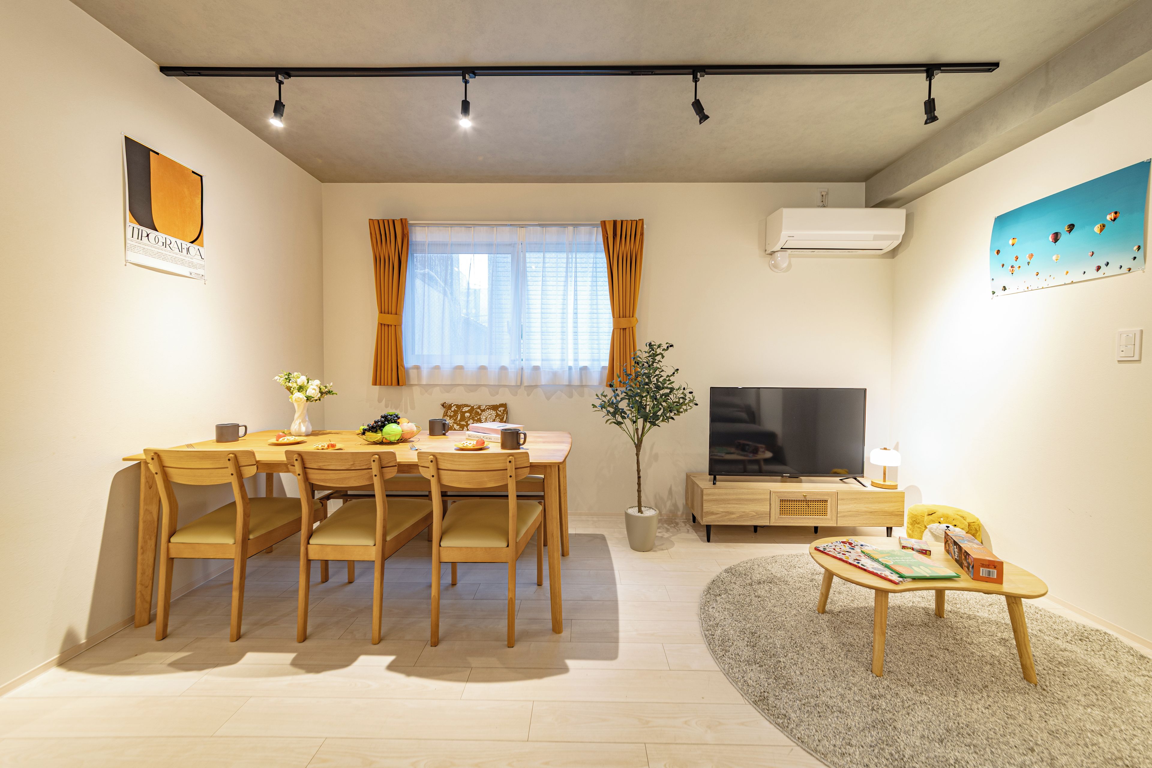 A modern living room with a dining table, chairs, a TV, and a small coffee table.