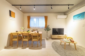 A modern living room with a dining table, chairs, a TV, and a small coffee table. - River Residence BOTAN by Tranova (Tokyo)