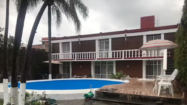 A two-story building with a swimming pool, outdoor seating, and potted plants. - Rest house for 16 people Xochitepec Morelos (Xochitepec)