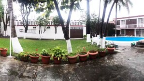 A courtyard with a swimming pool, potted plants, and a building with a balcony in the background. - Rest house for 16 people Xochitepec Morelos (Xochitepec)