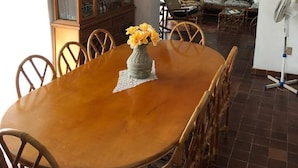 A dining area with a wooden table and chairs, a cabinet with glass doors, a vase with flowers, and a fan in the corner. - Rest house for 16 people Xochitepec Morelos (Xochitepec)