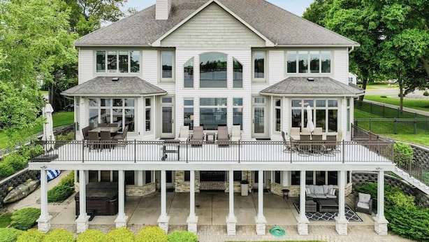 A large, two-story house with a covered patio and multiple windows. - Downtown Lakefront Home on Lake Chetek with hot tub & pontoon rental (Chetek)