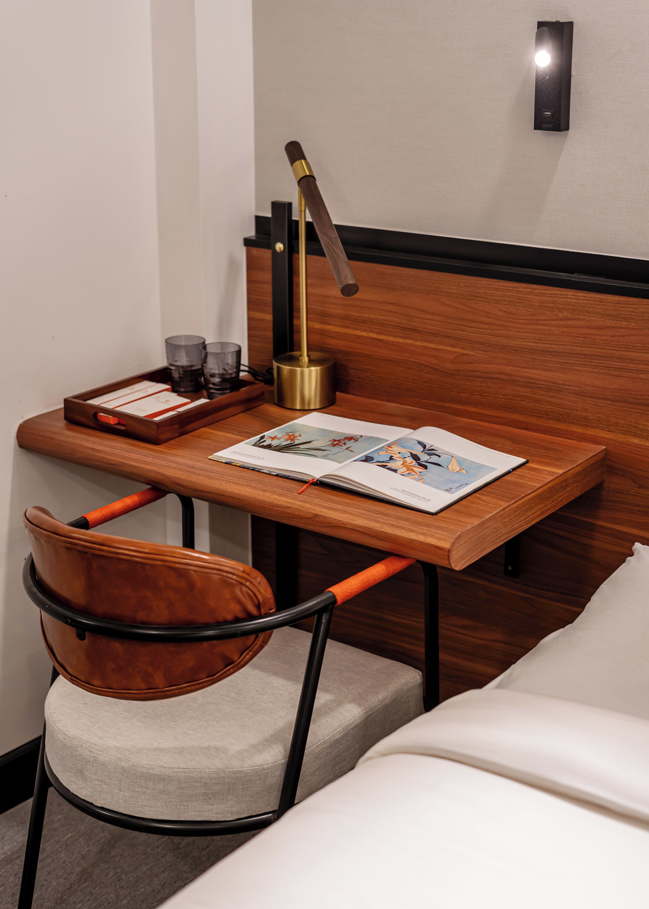 A small, neatly arranged workspace with a wooden desk, a leather chair, a lamp, and a magazine.