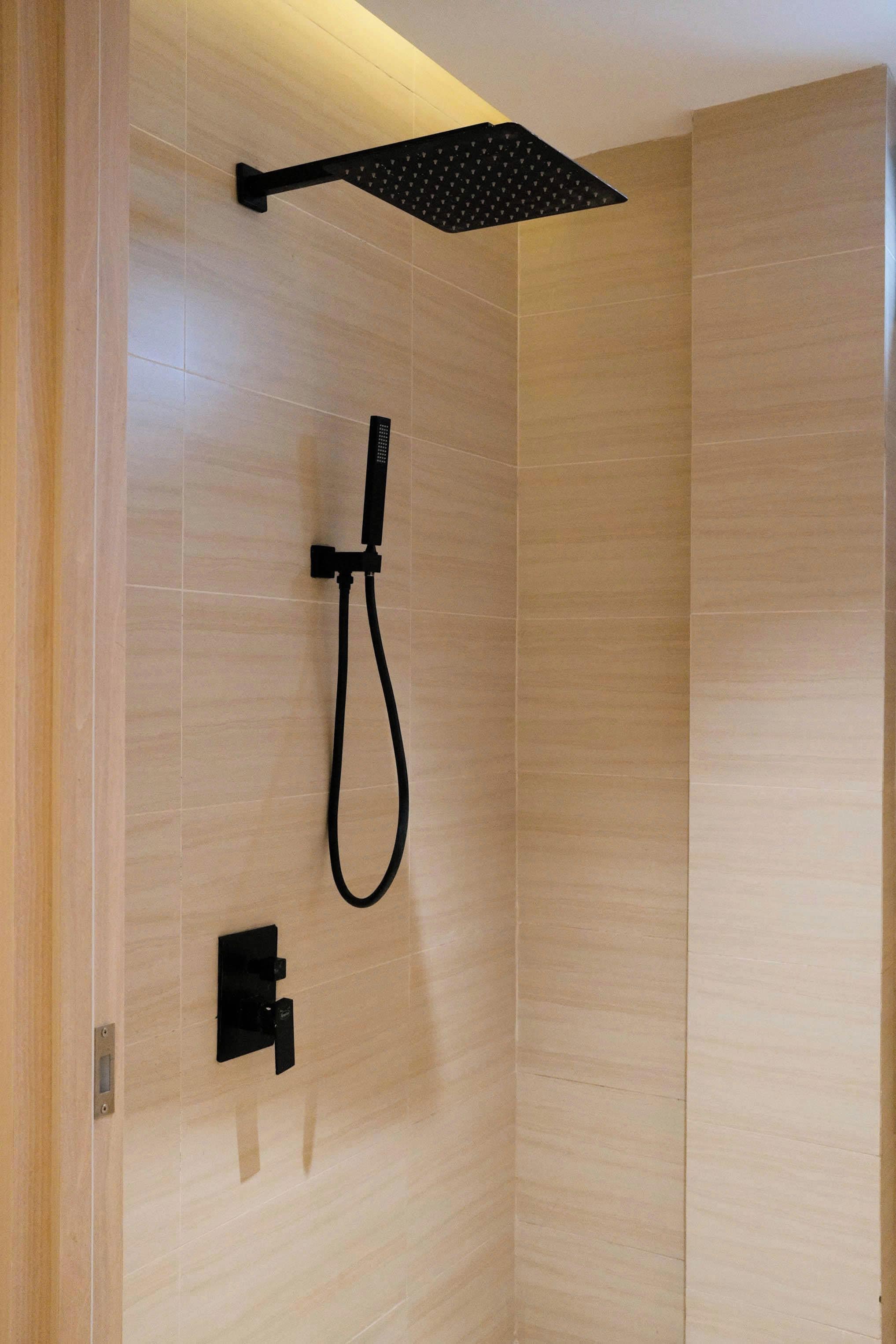 A modern shower with a handheld showerhead and a wall-mounted control panel.