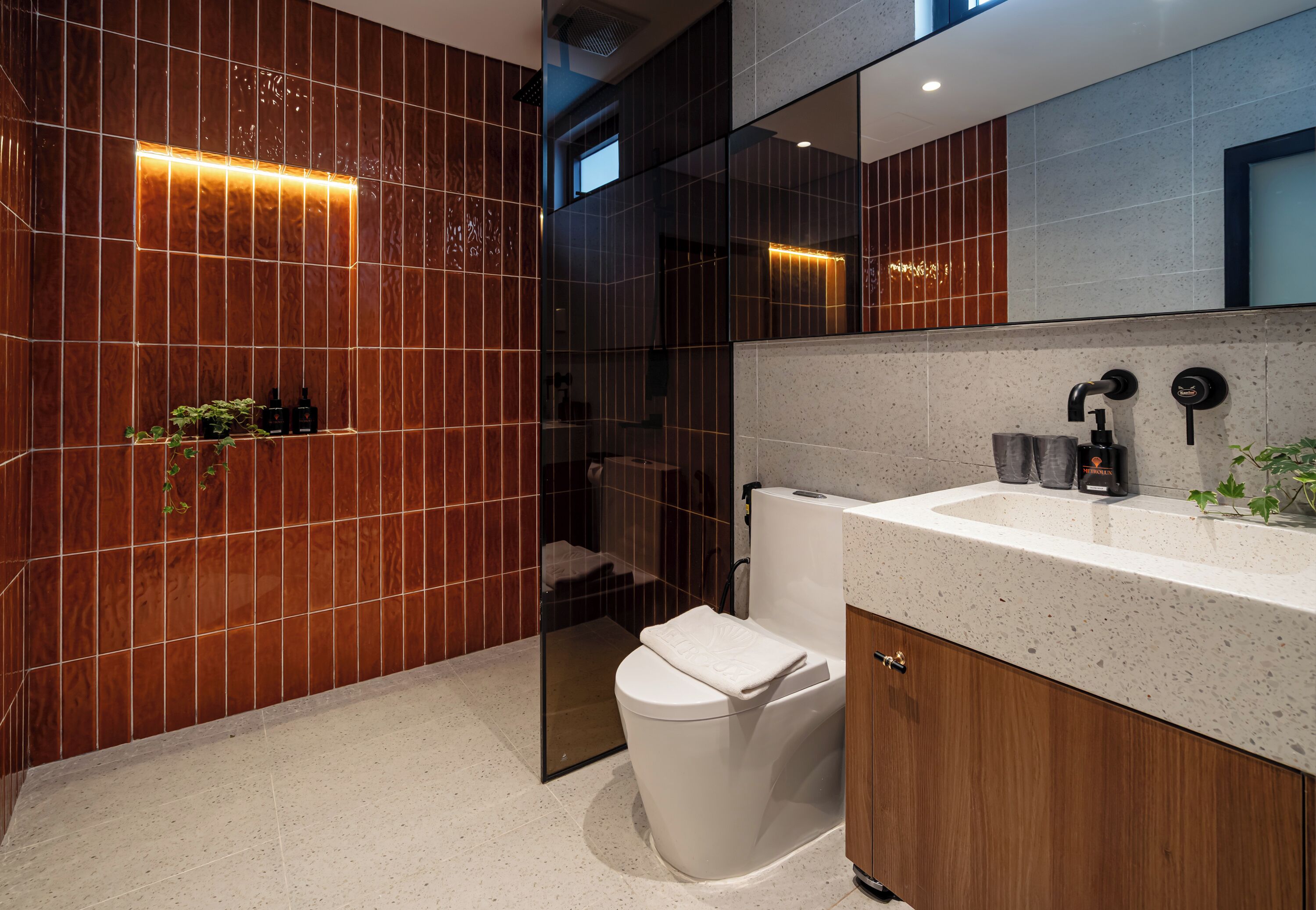 A modern bathroom with a white toilet, a sink with a speckled countertop, and a mirror above the sink.