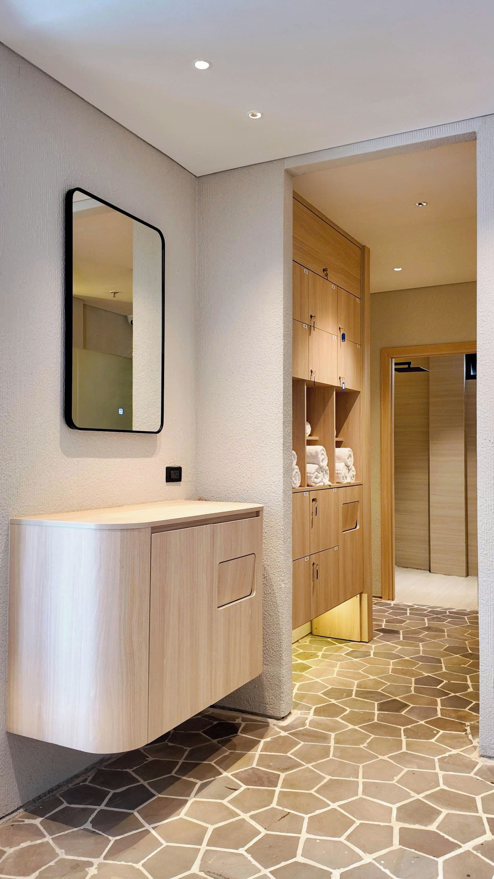 A bathroom with a wooden vanity, a mirror, and a tiled floor.