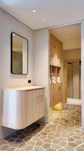 A bathroom with a wooden vanity, a mirror, and a tiled floor. - Metrolux City Contemporary Hotel (Ho Chi Minh City)