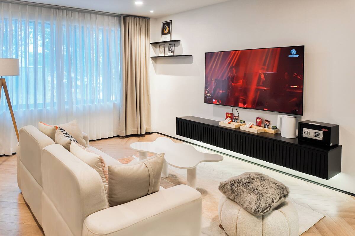 A modern living room with a sofa, a coffee table, and a flat-screen TV mounted on the wall.