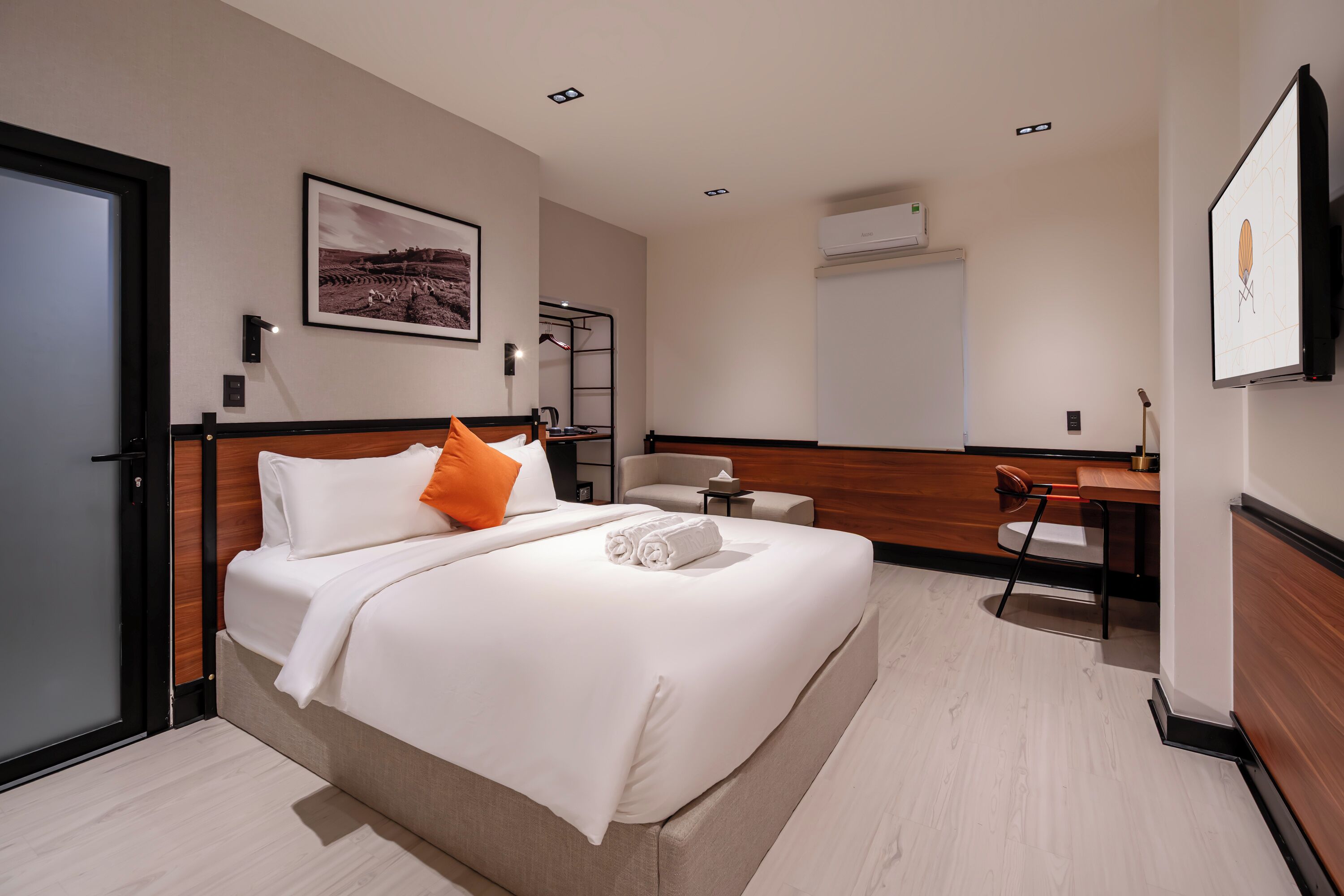 A modern hotel room with a large bed, a desk, and a chair.