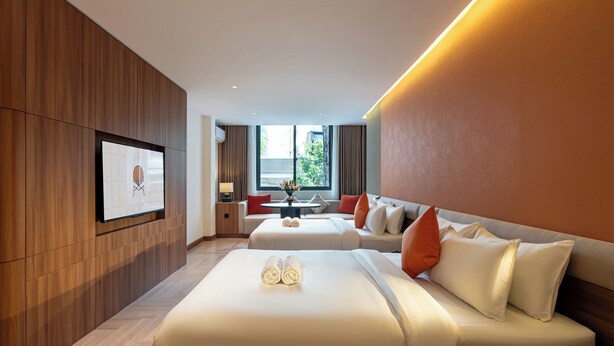 A modern hotel room with a large bed, a sofa, a dining table, and a TV mounted on the wall. - Metrolux City Contemporary Hotel (Ho Chi Minh City)