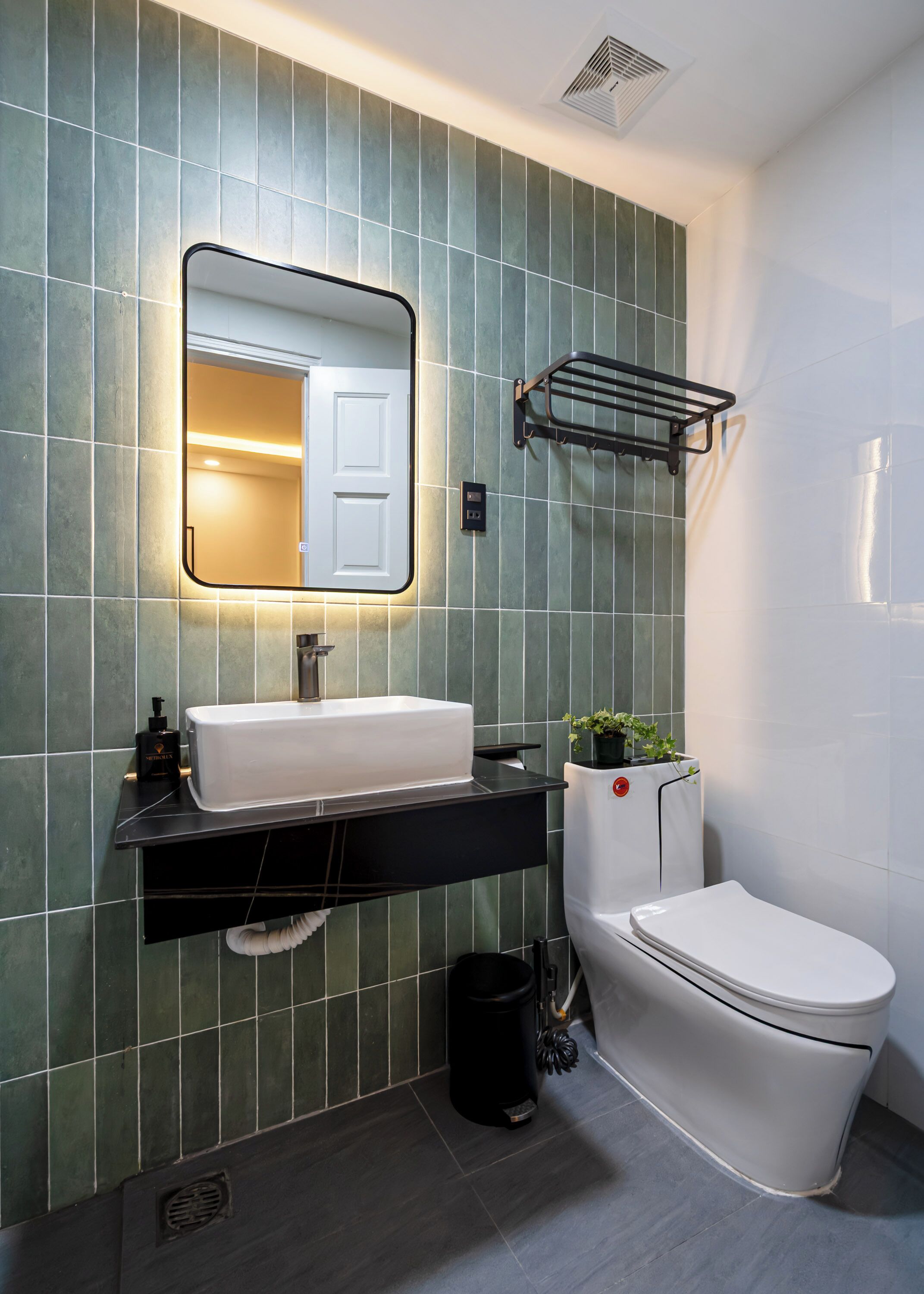 A modern bathroom with a rectangular mirror, a white sink, and a toilet.