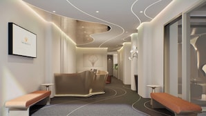 A modern reception area with a curved wall design, a bench, and a framed logo on the wall. - Metrolux City Contemporary Hotel (Ho Chi Minh City)
