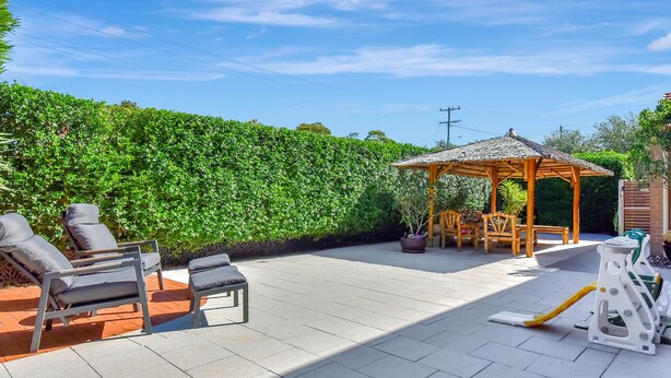 A patio with outdoor furniture, a gazebo, and a neatly trimmed hedge. - Nelly's Nest pet-friendly villa in Nelson Bay (Nelson Bay)