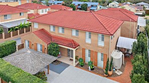 A residential building with a red-tiled roof, a covered patio area, and a water tank.