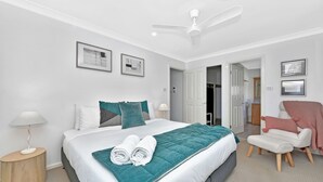 A modern bedroom with a bed, a chair, a desk, and a ceiling fan. - Nelly's Nest pet-friendly villa in Nelson Bay (Nelson Bay)