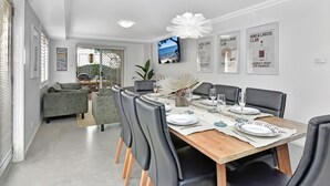A modern dining area with a wooden table set for six, surrounded by leather chairs. - Nelly's Nest pet-friendly villa in Nelson Bay (Nelson Bay)