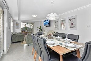 A modern dining area with a wooden table set for six, surrounded by leather chairs.