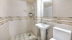 Egy fürdőszoba zuhanyzóval, mosdókagylóval és WC-vel.