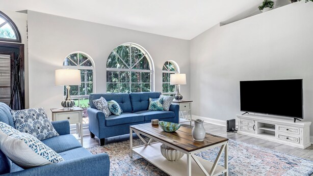 A living room with a blue sofa, two side tables with lamps, a coffee table, a flat-screen TV, and a decorative cabinet. - Charming 3-bedroom house with AC, WiFi in beautiful Naples (Naples)
