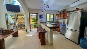 A modern kitchen with a central island, stainless steel appliances, and a dining area with wooden stools.