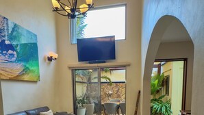 A spacious living room with a leather sofa, a wooden coffee table, and a television mounted on the wall.