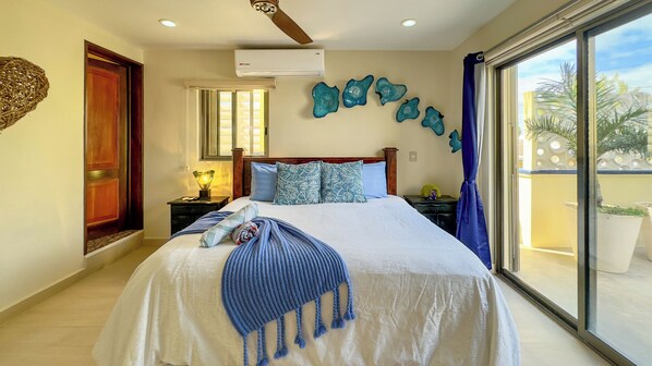 A hotel room with a bed, a nightstand, a lamp, a window with curtains, and a view of the outside.
