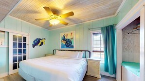 A bedroom with a bed, a ceiling fan, a window with curtains, and a wall with a turtle mural. - Charming Townhouse,  Shared pool, Great Location (Port Aransas)