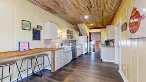 A kitchen with wooden flooring, white cabinets, and a bar area with stools. - Charming Townhouse,  Shared pool, Great Location (Port Aransas)