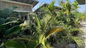 A modern building with a flat roof and large windows, surrounded by lush tropical vegetation including palm trees and various shrubs. - Treetop Bungalows (Siem Reap)