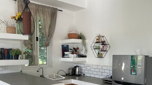 A modern kitchen with a central island, a stainless steel refrigerator, and a hanging light fixture. - Treetop Bungalows (Siem Reap)