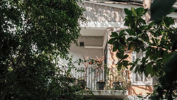 A multi-level building with balconies, surrounded by dense foliage and potted plants. - Treetop Bungalows (Siem Reap)