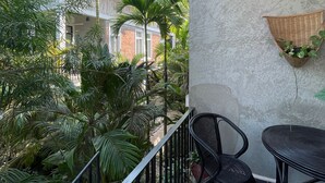 A balcony with a view of a garden, a table with chairs, and a hanging basket with plants. - Treetop Bungalows (Siem Reap)