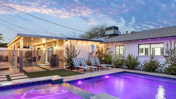 Ein modernes Haus mit Swimmingpool, Außenmöbeln und einer überdachten Terrasse.