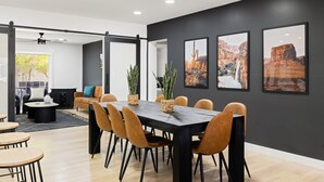 Ein moderner Essbereich mit einem dunkelholznen Tisch, orangefarbenen Stühlen und Blumentöpfen.