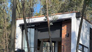 A modern house with a glass facade, a balcony, and a brick section. - Beautiful tiny home with amazing view and hot tub (Quito)