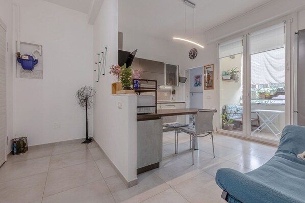 A modern apartment with a kitchen, dining area, and a balcony with outdoor furniture.