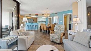 A spacious living room with a sofa, armchair, and dining area in the background.