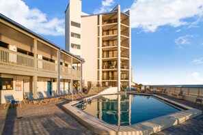 A hotel with a swimming pool, multiple balconies, and sun loungers.