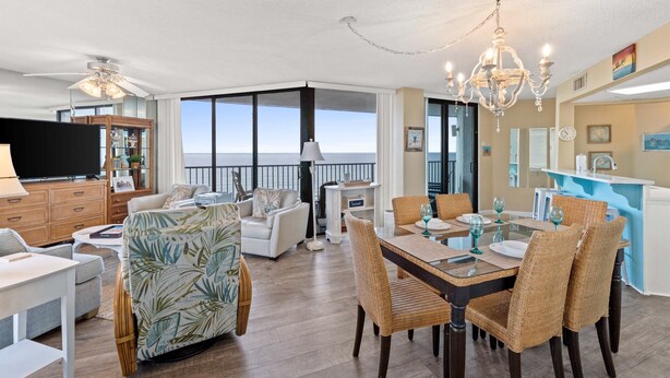 A spacious living area with a dining table, wicker chairs, and a view of the ocean.