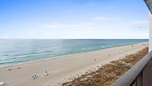 A beach with a clear sky, sandy shore, and a few beach chairs.