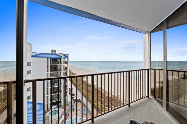 A balcony with a view of the beach and ocean.