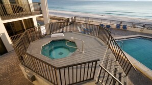 A rooftop pool area with a view of the beach, a hot tub, and a smaller pool.